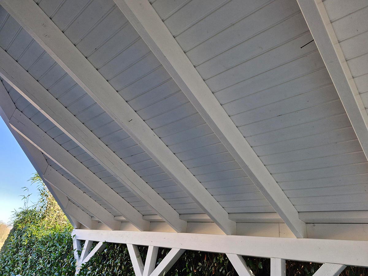 Weiss gestrichene Dachunterseite eines Carports mit sichtbaren Balken und Tageslicht