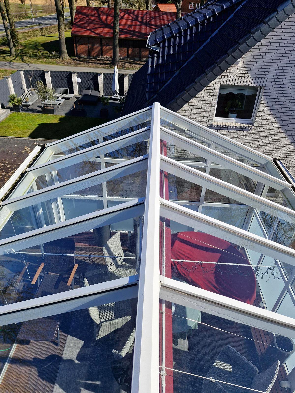 Wintergarten mit Glasdach von oben, darunter rote Tischdecke und graue Möbel