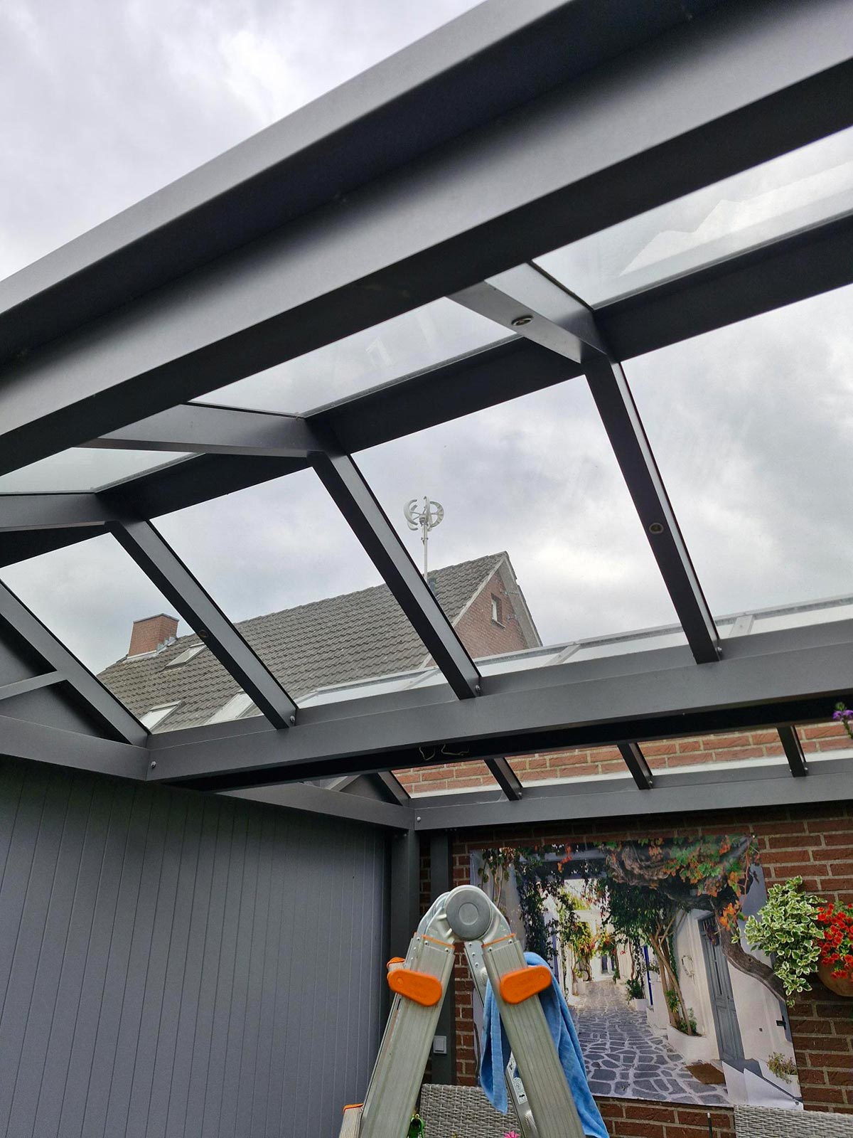 Blick auf einen grauen Winterhimmel durch ein Glasdach mit Leiter und Wandbild