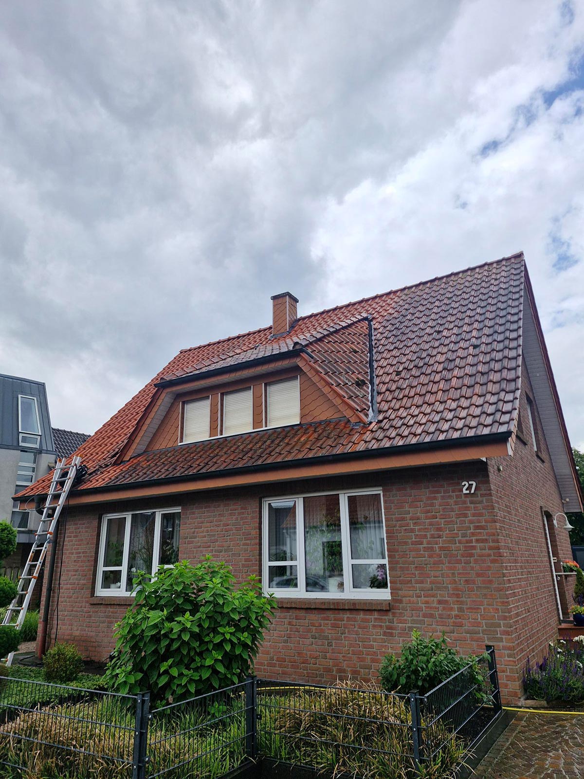 Ein rotes Ziegelhaus mit Satteldach und Dachfenstern vor bewölktem Himmel