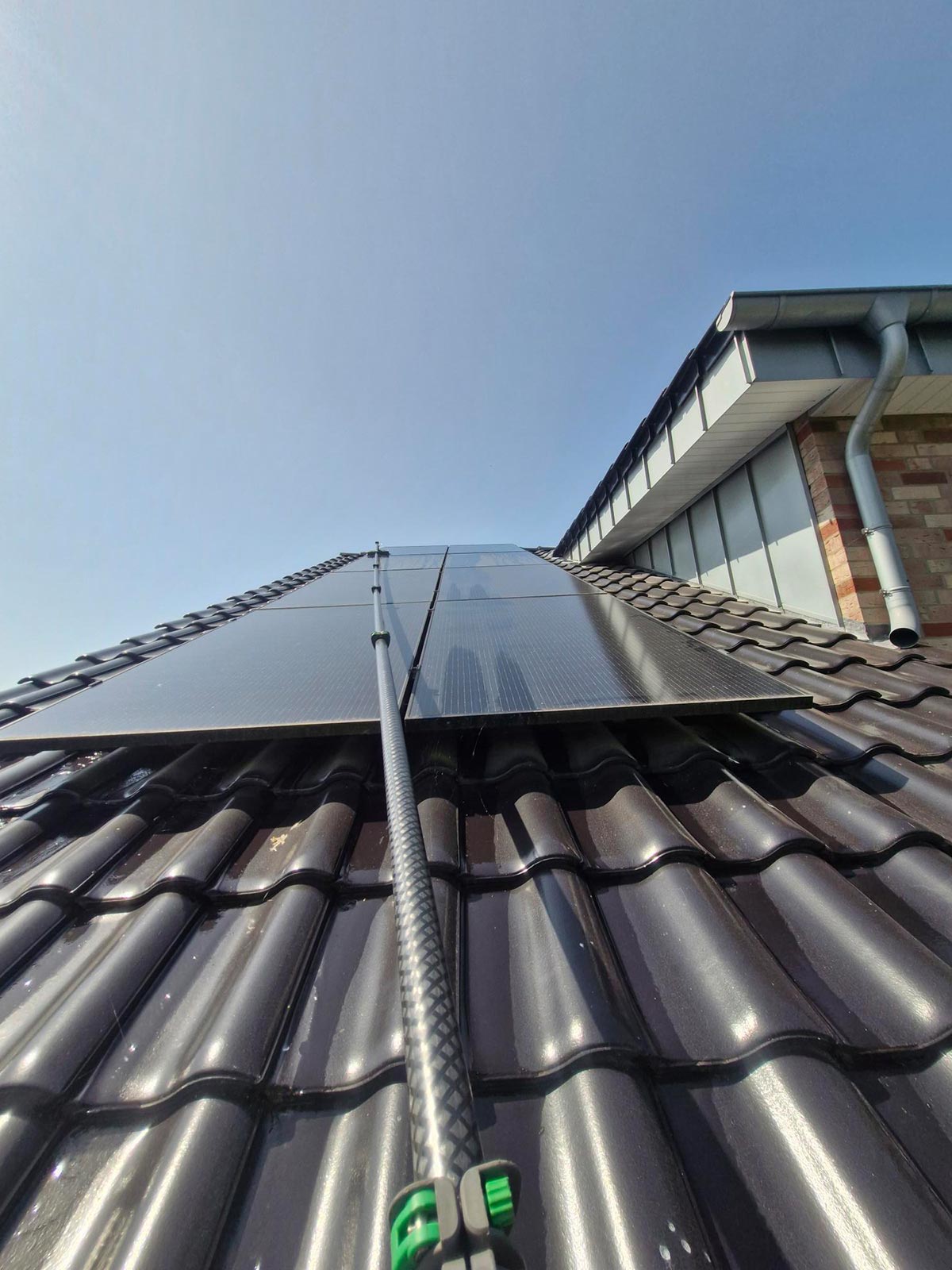 Schwarze Solarpanels glänzen auf einem Dach mit blauen Dachziegeln bei Sonnenschein